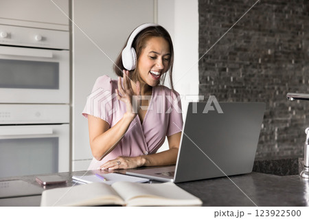 Pretty student woman wears headphones start video call on laptop 123922500