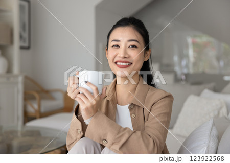 Happy relaxed beautiful young Asian woman drinking morning coffee Happy relaxed beautiful young Asian woman drinking morning coffee 123922568