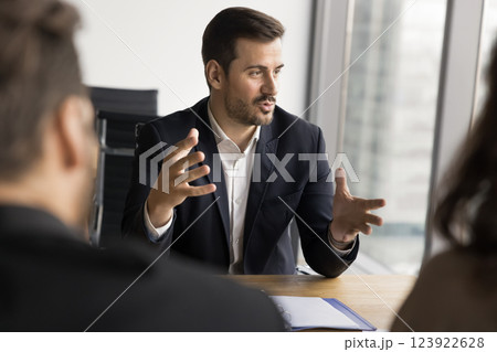 Businessman makes speech sits at table in front of shareholders Businessman makes speech sits at table in front of shareholders 123922628
