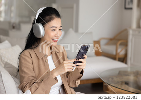 Happy Asian girl in big headphones talking on video call Happy Asian girl in big headphones talking on video call 123922683