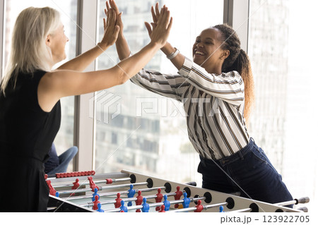 Colleagues playing table football, giving high five gesture, celebrate victory 123922705