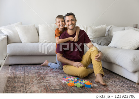 Dad and son sit on rug in cozy living room 123922706