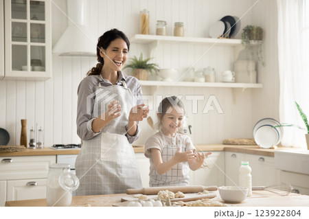 Laughing mum little daughter rolling dough clapping hands in flour Laughing mum little daughter rolling dough clapping hands in flour 123922804