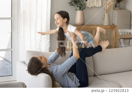Mom support little daughter in air with legs play flying Mom support little daughter in air with legs play flying 123922813
