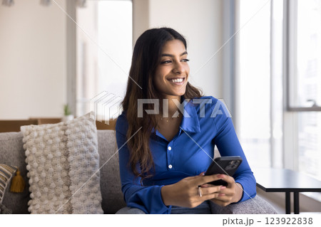 Indian female holding smartphone with thoughtful expression Indian female holding smartphone with thoughtful expression 123922838