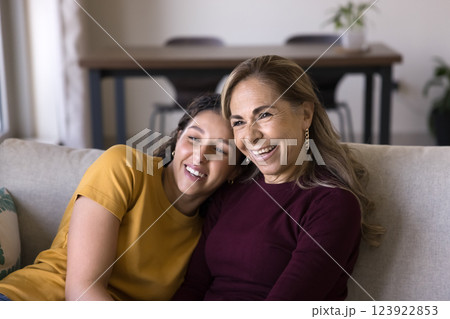 Cheerful Latina women spend free time relaxing seated on couch 123922853