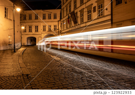 A quiet night on Letenska Street reveals blurred tram lights speeding through a tunnel. The cobblestones shine under street lamps casting a warm glow across the Lesser Town. 123922933