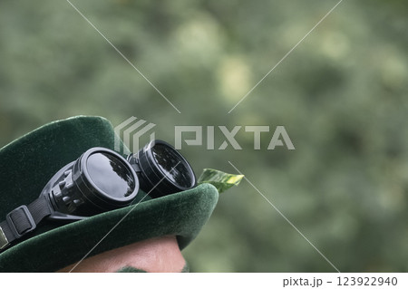 The pilot's glasses rest atop a green hat, concealing the individual's face from view.. Amidst a serene backdrop, trees extend in every direction, providing a sense of tranquility and natural beauty. 123922940