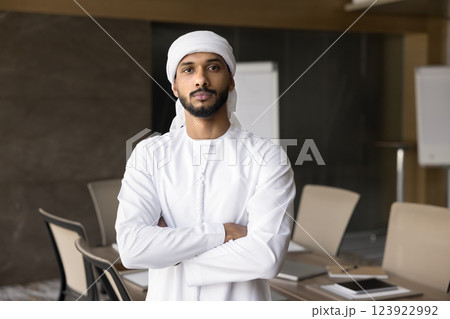 Young self-assured Middle Eastern businessman posing in modern conference room Young self-assured Middle Eastern businessman posing in modern conference room 123922992