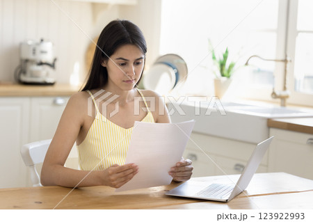 Young woman thinking over paper documents at home office desk 123922993