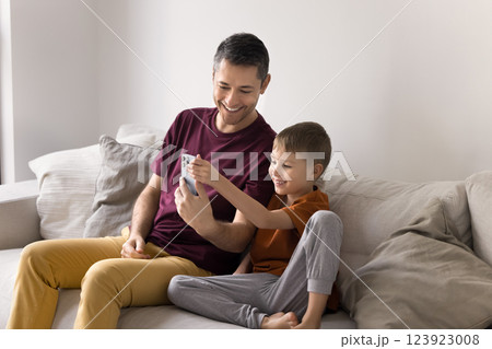 Dad and son sit together on cozy sofa with smartphone 123923008