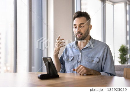 Serious Hispanic man speaking to client through videocall 123923029
