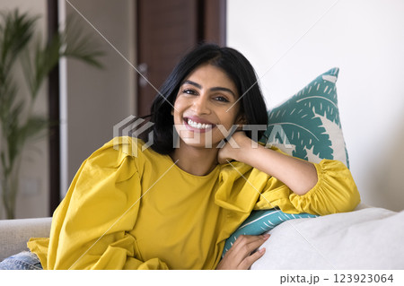 Portrait of happy Indian woman relaxing seated on comfortable couch Portrait of happy Indian woman relaxing seated on comfortable couch 123923064