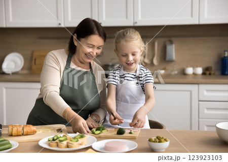 Loving older granny teach to cook little grandkid girl Loving older granny teach to cook little grandkid girl 123923103