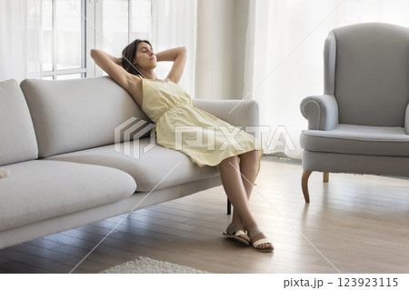 Happy young female rest hands behind head on comfortable sofa 123923115