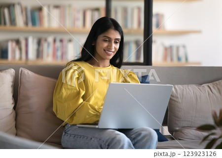 Happy young female use notebook on sofa at home office 123923126