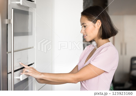 Woman adjusting settings on modern kitchen appliance 123923160