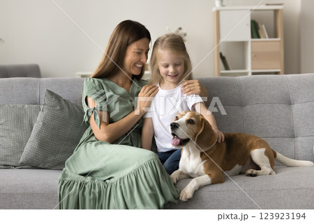 Kid stroking beagle dog seated together on sofa with mom Kid stroking beagle dog seated together on sofa with mom 123923194