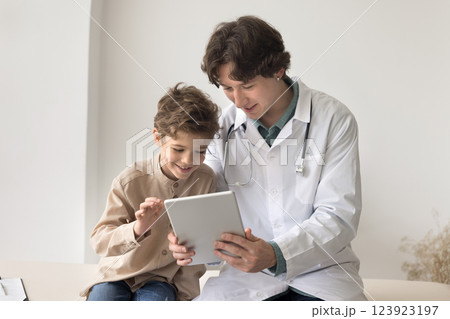 Young male doctor use tablet on meeting with little boy 123923197