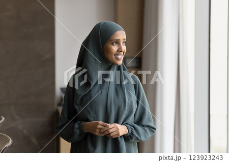Confident Arabian elegant businesswoman dressed in hijab, standing near window 123923243