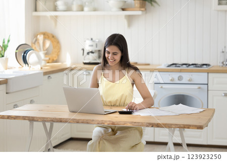 Smiling young female engaged in accounting work at home office 123923250