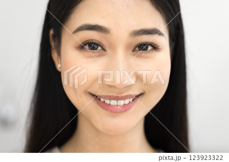Young 25s Asian woman looking at camera, cropped face view 123923322