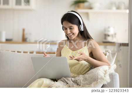 Happy gen z woman in headset making videocall on notebook Happy gen z woman in headset making videocall on notebook 123923343