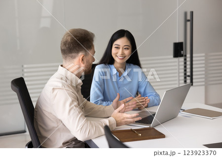 Confident young businessman consulting young Asian female using notebook 123923370