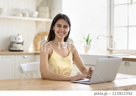 Happy smiling young woman sitting by notebook looking at camera 123923392