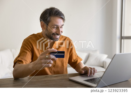 Smiling Portuguese 40s man doing online shopping at home 123923395