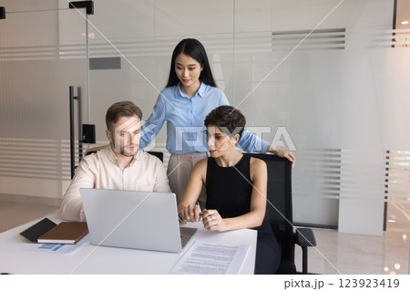 Young Asian woman team leader supervise two diverse interns work Young Asian woman team leader supervise two diverse interns work 123923419