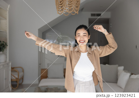 Cheerful beautiful 20s Asian girl dancing at new home Cheerful beautiful 20s Asian girl dancing at new home 123923421