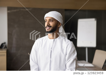 Pensive Arabian entrepreneur looks into distance with smile Pensive Arabian entrepreneur looks into distance with smile 123923459