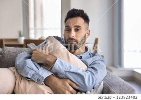 Lonely man hugging pillow deeply immersed in watching romantic movie 123923482