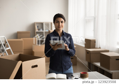 Portrait smiling young female internet shop manager holding digital pad Portrait smiling young female internet shop manager holding digital pad 123923508
