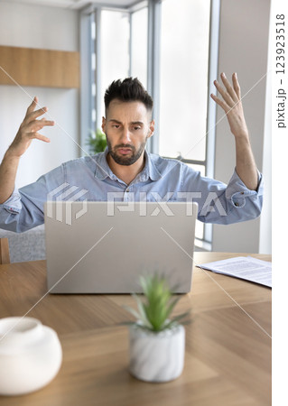 Annoyed man using laptop experiences problems with device 123923518