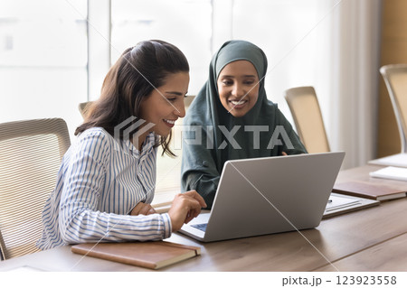 Two multicultural women engaged in collaborative activity on laptop 123923558