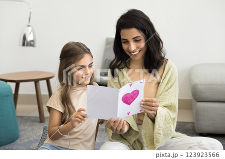 Cute little daughter presenting to mommy lovely postcard on birthday 123923566