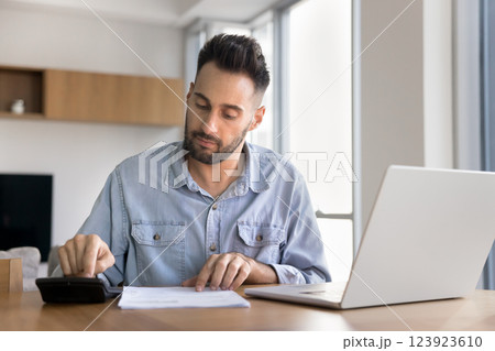 Focused man engaged in financial work seated at table Focused man engaged in financial work seated at table 123923610