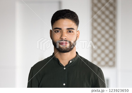 Young Arabic man standing indoors with serious expression 123923650