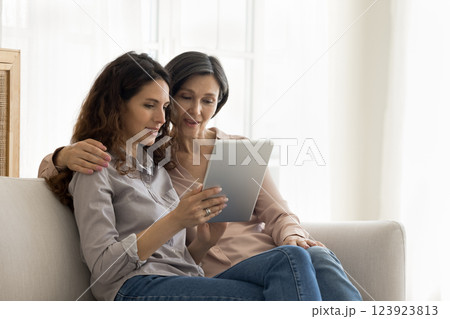 Caring adult daughter with mature mom using tablet on sofa Caring adult daughter with mature mom using tablet on sofa 123923813