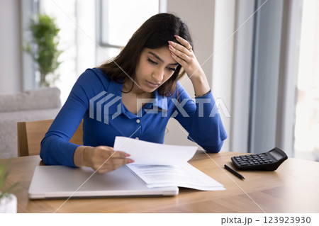 Woman reading bad news in letter with concerned expression 123923930