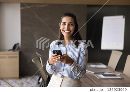 Portrait of smiling businesswoman stands in conference room with smartphone 123923969