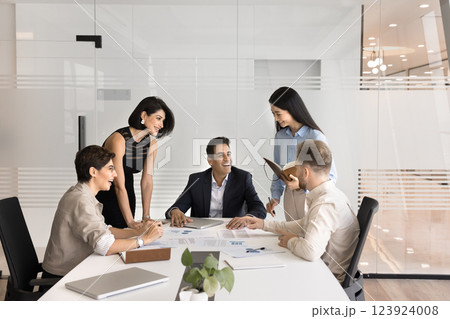 Diverse multiethnic workers group gather by table for informal conversation 123924008