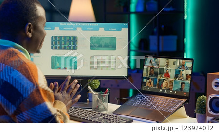 African american male freelancer attends virtual meeting call with clients on laptop, working at home and sharing insight on income statistics. Person listening to video call. Camera A. 123924012