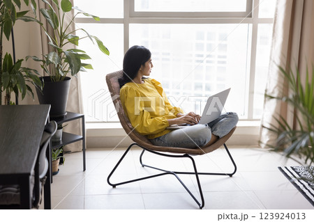 Woman sit comfortably in modern chair holding laptop on lap Woman sit comfortably in modern chair holding laptop on lap 123924013