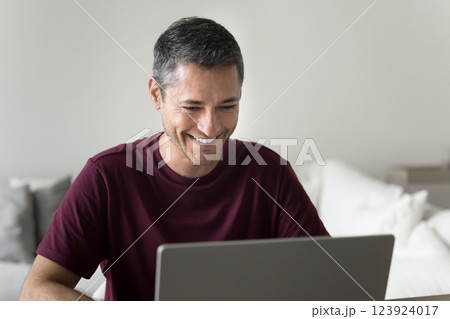 Young man sitting at desk working or studying using laptop 123924017