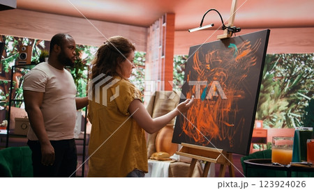 Team of artists in a gallery atelier working on new art piece, using finger painting technique for abstract creation. Blending acrylic paints with precision to create contemporary design. Camera B. Team of artists in a gallery atelier working on new art piece, using finger painting technique for abstract creation. Blending acrylic paints with precision to create contemporary design. Camera B. 123924026