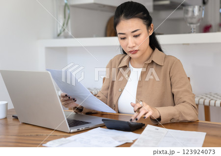 Serious focused Asian freelance bookkeeper woman working from home Serious focused Asian freelance bookkeeper woman working from home 123924073