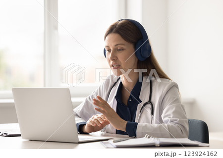 Young woman doctor in headset speak with patient by videocall 123924162
